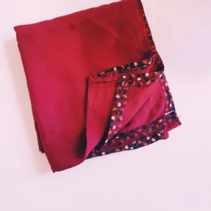 Röd sjal med broderad kant - Snygg röd halsduk med broderad kant i flera färger. Tunt och mjukt tyg som ger ett elegant intryck. Perfekt att slänga över axlarna för en extra touch till din outfit.  Tjockare tyg Helt & fint skick dock tvättludd