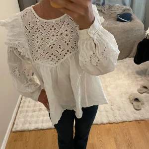 Vit blus med broderade detaljer - Superfin vit blus med broderade hålmönster och volangdetaljer på axlarna❣️
