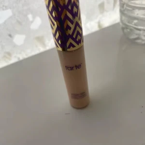 Tarte Shape Tape Concealer - Tarte Shape Tape Concealer i en ljus beige nyans. Kommer i en snygg tub med lila och guldigt mönster på locket. Perfekt för att täcka mörka ringar och ojämnheter med en krämig formula. Förpackningen finns 