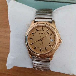 Tissot PR 50 guld/silver herrklocka - Klassisk Tissot PR 50 med guldfärgad urtavla och boett, samt silverfärgat armband i rostfritt stål. Klockan har datumvisning och safirglas. Snygg och stilren design som passar till många olika looks. Onesize armlänk.