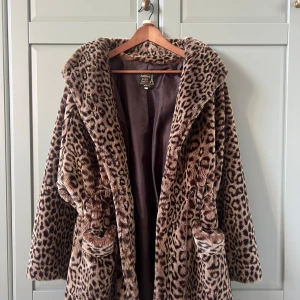 Leopardmönstrad pälsjacka Aniral Paris - Säljer en fluffig och oversized pälsjacka från Aniral Paris med leopardmönster i bruna och svarta toner. Jackan har stora slag, fickor och är helfodrad. Perfekt statement-plagg för dig som vill sticka ut med en lyxig vibe. Jackan har axelinlägg och snörning i midjan. 