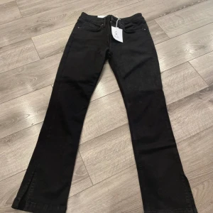 Svarta jeans med slits nertill - Snygga svarta jeans med raka ben och diskret slits nertill. Klassisk femficksmodell i stretchigt jeanstyg som sitter skönt. Perfekta till sneakers eller boots för en clean look.