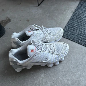 Vita Nike Shox sneakers med silvriga detaljer - Nike Shox sneakers i vitt med silvriga detaljer och röd logga på plösen. Änvänd ett par gånger väldigt bra skick. Äkta!!!!