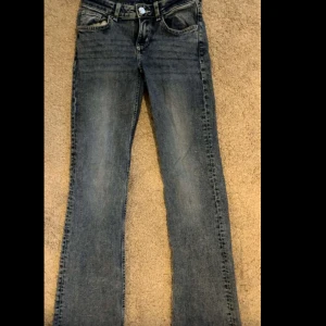 Blå bootcut jeans midwaist stl 32/xxs - Snygga blå jeans med bootcut passform och klassisk femficksdesign. Jeansen har en låg midja och är tillverkade i jeansmaterial med lätt tvättad look. Perfekta för dig som gillar en tidlös stil med lite utsvängda ben.