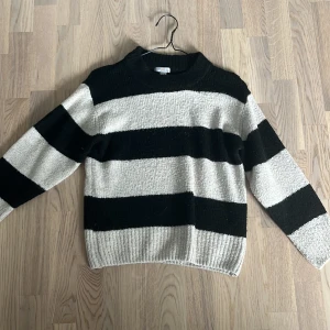 Randig stickad tröja från Gina Tricot - Säljer en svartvit stickad tröja från Gina Tricot i storlek 146/152. Tröjan har breda horisontella ränder, rund hals och långa ärmar. Perfekt för dig som gillar en chill och trendig look med lite oversized känsla.
