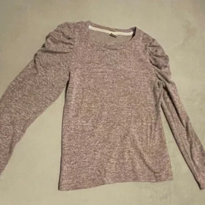 Ljuslila långärmad tröja med puffärm - Superfin ljuslila långärmad tröja med diskreta puffärmar vid axlarna. Mjuk och skön, perfekt till jeans eller kjol. Materialet känns stretchigt och lätt, och färgen är melerad i lila toner. Enkel rund halsringning och smal passform.