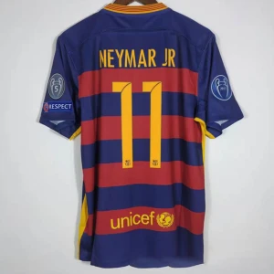 Barcelona Neymar Jr 11 matchtröja - Säljer en ikonisk FC Barcelona fotbollströja med Neymar Jr och nummer 11 på ryggen. Tröjan är kortärmad, har breda blå och röda ränder, gula detaljer och officiella Champions League-märken på ärmarna. Perfekt för dig som älskar fotboll och vill sticka ut.