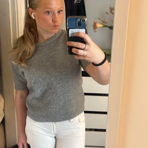 Grå stickad kortärmad tröja från Zara - Supermysig grå stickad tröja från Zara med korta ärmar och rund hals. Perfekt till jeans eller kjol för en chill och stilren look. Tröjan har ribbade kanter vid ärmslut och nederkant och är i en mjuk, lite luddig stickad kvalitet.
