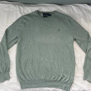 Ralph lauren tröja stickad slim fit - Snygg grå/blå/grön långärmad tröja från Polo Ralph Lauren i slim fit-modell. Tillverkad i mjuk pima bomull med diskret broderad logga på bröstet. Perfekt för dig som gillar stilren och klassisk look med en modern touch.