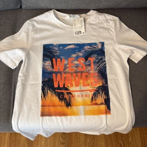 Vit t-shirt West Waves H&M - Vit t-shirt från H&M med färgglatt tryck på framsidan där det står 'West Waves California' i orange. Motiv med palmer och solnedgång i blått och orange. Klassisk passform och rund hals. Perfekt för en chill sommarlook. Helt ny med prislapp.