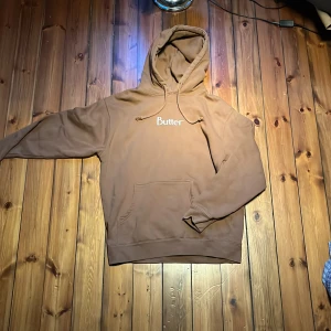 Brun hoodie från Butter, medium - Säljer en brun hoodie från Butter i storlek medium. Tröjan har huva med snörning, magficka och enkel logga på bröstet. Skön och avslappnad passform, perfekt för chill dagar. Materialet är mjukt och känns som bomull eller fleece. Kom med frågor pruta för en snabb affär 