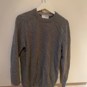 Grå stickad tröja från Selected Homme - En klassisk grå stickad tröja från Selected Homme med rund halsringning och ribbade muddar. Perfekt för lager-på-lager och enkel att matcha med jeans eller chinos. Skön och stilren för dig som gillar en clean look.