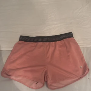 Rosa träningsshorts från SOC - Snygga rosa träningsshorts från SOC med svart elastisk midja i mesh. Lätta och luftiga med sportig känsla, perfekta för gymmet eller löprundan. Klassisk design med liten logga framtill. Supersköna att röra sig i och passar dig som gillar en aktiv livsstil.