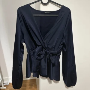 Mörkblå omlottblus från Missäy - Snygg mörkblå omlottblus från Missäy med långa ärmar och knyt i midjan. Marinblå färg! Använd fåtal gånger!