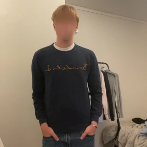 Mörkblå sweatshirt från Bondelid XS - Säljer en mörkblå sweatshirt från Bondelid i storlek XS. Tröjan har ett snyggt broderat Bondelid-tryck i gult över bröstet och är tillverkad i mjuk bomull. Klassisk rund halsringning och långa ärmar, perfekt för en chill och stilren look.