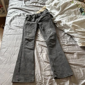 Grå bootcut jeans från H&M, stl 158 - Snygga grå bootcut jeans från H&M i storlek 158. Jeansen har låg midja, justerbar midja och coola bakfickor med lock och knappar. Klassisk femficksmodell med dragkedja och dubbla knappar framtill. Perfekta till sneakers eller boots.