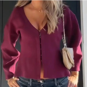 Vinröd cardigan jacka med v-ringning - Snygg vinröd cardigan jacka med djup v-ringning och långa ärmar. Jackan har en enkel, stilren design med knäppning framtill och är perfekt att slänga över en topp. Materialet ser mjukt och bekvämt ut, och passformen är normal.