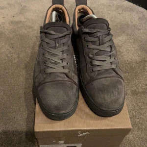 Gråa Christian Louboutin Sneakers - Säljer nu dessa snygga Christian Louboutin mocha sneakers i storlek 44 eftersom de nu tyvärr  blivit för små, skick 8/10 då skorna är använda och har lite slitage på sulorna samt ett litet hål vid hälen men det är ingenting som man lägger märke till. Lådan, alla  original papper, en sidenväska eller så kallad ”travelbag” samt ett kort med äkthetsbevis medkommer vid köp. Det är bara att höra av er vid eventuella frågor eller funderingar😊