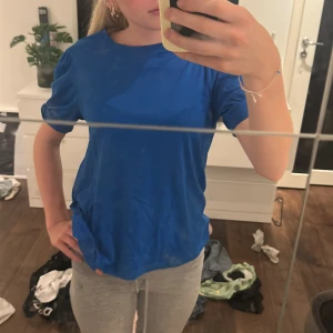 Blå t-shirt från Vero Moda Aware XS - Snygg blå t-shirt från Vero Moda Aware i storlek XS. Enkel och stilren design med rund halsringning och korta ärmar. Tillverkad i mjuk bomull som känns skön mot huden. Perfekt till jeans eller shorts för en chill look.