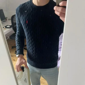 👕 Marinblå Ralph Lauren Kabelstickad Tröja - 100% Bomull 🧶 -  *   Storlek: S *   Material: 100% Bomull - supermjuk och skön! ☁️ *   Modell: Klassisk kabelstickning *   Detaljer:     *   Ribbstickade muddar och nederkant     *   Liten, diskret Ralph Lauren-logga 🐎 *   Passform: Normal passform - bekväm och stilren *   Skick: Perfekt för kyliga dagar! ❄️ *   Modell: 176 cm, ca 63 kg 🏋️‍♂️ *   Stil: Perfekt för en avslappnad men sofistikerad look! ✨