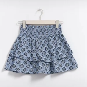 Blå mönstrad volangkjol - Supersöt blå kortkjol med volanger och ett unikt grafiskt mönster. Kjolen har en smockad midja som ger en bekväm passform och extra volym. Perfekt för dig som vill ha en lekfull och trendig look till sommaren.