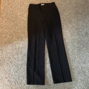 Svarta kostymbyxor från Madlady - Snygga svarta kostymbyxor från Ballantyne med klassisk rak passform och pressveck. Byxorna har fickor i sidorna och är perfekta för en stilren look. Materialet känns mjukt och följsamt.