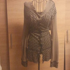 Mönstrad kofta från Anna Field, stl 44 - Supersnygg kofta från Anna Field i beige och svart med coolt mönster framtill. Koftan har långärmade ärmar, knappar och snörning i midjan för extra detalj. Mjuk stickad känsla och bred krage som ger en chill vibe.