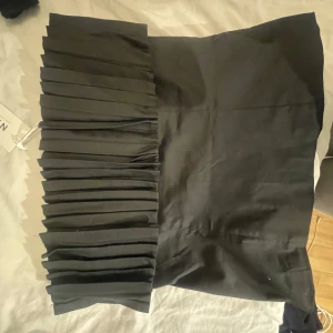Svart axelbandslös topp från NA-KD - Säljer en svart axelbandslös bandeau topp från NA-KD med plisserad överdel. Helt ny, med lappen kvar 
