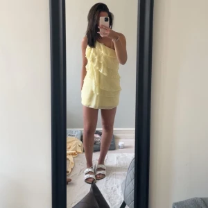 Gul one shoulder volangklänning - Säljer en söt ljusgul kortklänning med one shoulder och flera volanglager framtill. Använt en gång storlek S💛