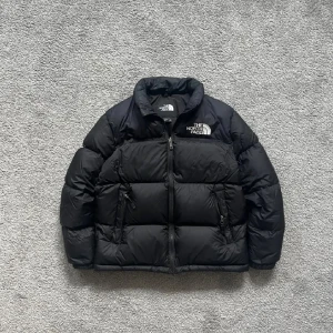 Svart dunjacka från The North Face - Säljer min äkta The North Face dunjacka i klassisk svart. Jackan är i överlag mycket bra skick, varm, stilren och perfekt för höst och vinter. Passar både till vardags och mer streetwear inspirerade outfits.  🔹 Storlek: M 🔹 Färg: Svart 🔹 Originalpris: 3000  Skick: Jackan är väl omhändertagen men har två små skönhetsfel: – Två pyttesmå hål på ryggen (syns på sista bilden) – Några tänder saknas i dragkedjan, men den fungerar fortfarande  Inga fläckar eller andra defekter. Alla knappar och fickor f