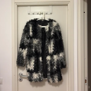 Svartvit pälsjacka från Zara Basic - Säljer en fluffig och statement svartvit pälsjacka från Zara Basic. Jackan har långa ärmar, coolt lockigt fuskpälsmaterial och ett mönster i svart, grått och vitt. Perfekt för dig som vill sticka ut och hålla dig varm under kalla dagar. Pris kan diskuteras 
