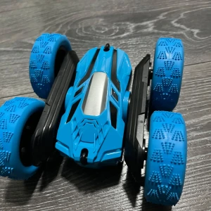 Blå leksaksbil  - Bilderna visar en blå leksaksbil med stora, mönstrade hjul och futuristisk design. Ljulen snurrar 360 grader.