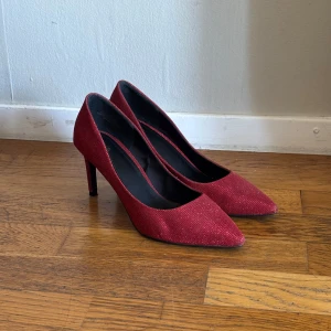 Röda glittriga pumps  - Snygga röda pumps från H&M med glittrig finish och spetsig tå ✨Skorna har hög klack och en elegant, smal siluett. Perfekta för dig som vill sticka ut med en färgstark och trendig look!