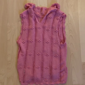Rosa stickad kortklänning från Zara - Supersöt rosa stickad kortklänning från Zara med volangkrage och ärmlös design. Klänningen har virkade detaljer och små blommor i strukturen, vilket ger en gullig och unik look. Perfekt för dig som vill sticka ut med en färgglad och lekfull stil.
