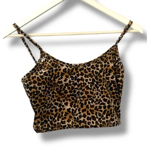 Leopardmönstrad croppad linnetopp - Säljer en croppad linnetopp med leopardmönster och tunna axelband. Toppen har en snygg, figurnära passform och är perfekt för dig som vill sticka ut. Materialet känns mjukt och stretchigt, vilket gör den superbekväm att bära.