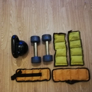 Träning för armar - Bilden visar träningsutrustning som hantlar, kettlebell och vikter för handleder eller vrister. Ingen bok syns på bilden.