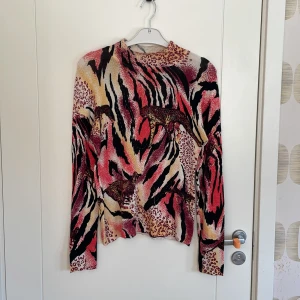 Leopardmönstrad tröja Papareil - Unik långärmad tröja från Papareil med leopardmönster och broderade pärlor. Färgerna går i rött, svart, beige och rosa med inslag av gult. Tröjan har en slim passform och coola djurdetaljer som verkligen sticker ut. Perfekt för dig som vill ha något annorlunda. Tröjan saknar lite pärlor med det syns inte särskilt mycket alls. 