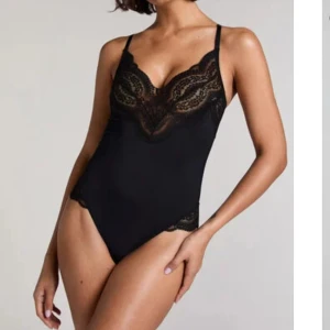 Svart spetslinnetopp med tunna band - Supersnygg svart linnetopp med tunna axelband och vacker spetsdetalj vid byst och nederkant. Toppen är figurnära och har en feminin, elegant look som passar perfekt till höga jeans eller kjol.