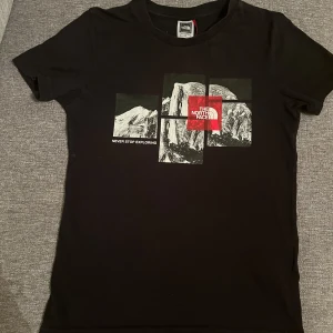 Svart t-shirt från The North Face(Barn storlek) - Svart t-shirt från The North Face med coolt grafiskt tryck av berg och röd logga på bröstet. Klassisk passform och rund halsringning, perfekt för dig som gillar äventyr och streetstyle.