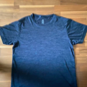 Blå tränings-tshirt från SOC - Gym tröja Säljer en blåmelerad t-shirt från SOC i storlek M T-shirten har rund halsringning och korta ärmar, perfekt för träning eller chill. Materialet är mjukt och andas, vilket gör den skön att ha på sig under aktiva dagar.