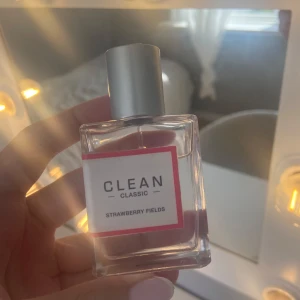 CLEAN Classic Strawberry Fields parfym - Fräsch parfym från CLEAN Classic i doften Strawberry Fields. Flaskan är rektangulär i genomskinligt glas med en silvrig metallkork och vit etikett med rosa kant. Doften har en söt och fruktig karaktär med inslag av jordgubb. Perfekt för dig som gillar lätta och bäriga parfymer.
