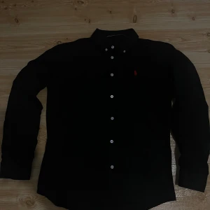 Svart Ralph Lauren skjorta  - En Ralph lauren skjorta som jag använt några gånger men är i perfekt skick. Inga skador osv. Storleken är XL på den men passar mig utmärkt som har M/L. 