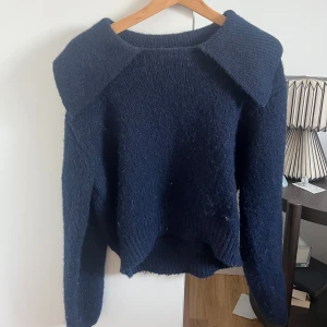 Mörkblå stickad tröja från Zara - Säljer en mörkblå stickad tröja från Zara med en unik krage. Tröjan har långa ärmar och en mjuk, mysig känsla. Perfekt för kyliga dagar eller till sommarkvällar. Hör av dig vid intresse! 💙