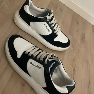 Svartvita sneakers från Valentino - Snygga svartvita sneakers från Valentino med klassisk design och snörning. Perfekta för en stilren look.