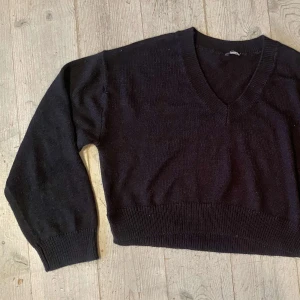 Svart stickad tröja med v-ringning - Säljer en stilren svart stickad tröja med v-ringning. Tröjan har långa ärmar och ribbade muddar vid ärmslut och nederkant. Perfekt för kyligare dagar.