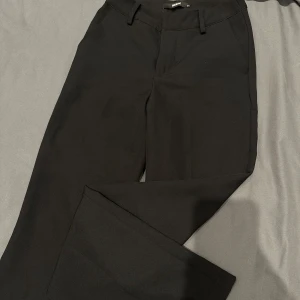 Svarta kostymbyxor från BikBok - Snygga svarta kostymbyxor från BikBok i storlek 34. De har en klassisk design med hällor för bälte och en stilren look. Perfekta för en chic och elegant stil.