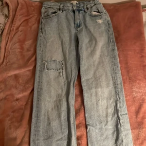Ljusa jeans med slitningar - Snygga ljusa jeans med slitningar på benen. Från Gina. De har en klassisk femficksdesign och en avslappnad passform. Perfekta för en casual look.