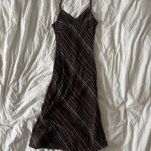 Brun klänning med mönster - Snygg brun klänning med tunna axelband och diagonala ränder i olika färger. Står storlek 40 men liten i storleken, passar XS-S