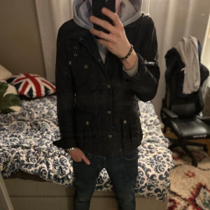 Barbour field jacket  - Snygg svart quiltad jacka med knappar och dragkedja. Jackan har flera fickor och en stilren design som passar perfekt för kyligare dagar. Perfekt för dig som vill ha en praktisk och trendig jacka.