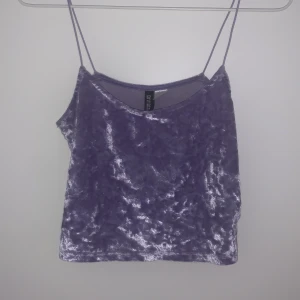 Lila glittrig linnetopp från H&M Divided - Säljer en snygg lila glittrig linnetopp från H&M Divided. Toppen har tunna axelband och är perfekt för en kväll ute. Materialet är mjukt och skimrande vilket ger en festlig look. Passar bra till både jeans och kjol. 🌟 Färgen har försvunnit en del där storleken står men i övrigt inget fel.